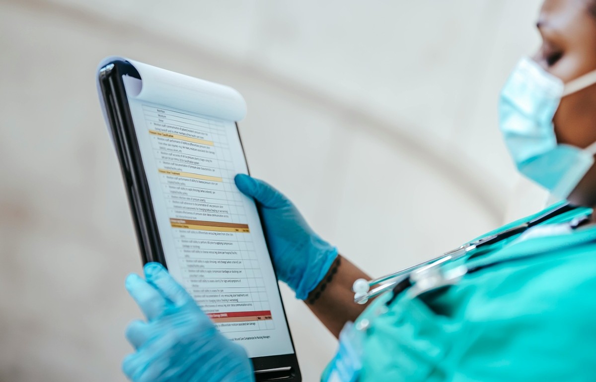 Healthcare professional reviewing clinical compliance documentation on a tablet